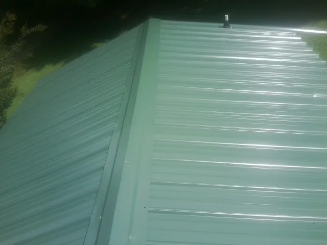 New green metal panels meeting at the ridge of a roof — Flat Roof Repair work by our crew in Great Mills