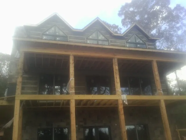 Dormers and porch framing on a large log home under construction — Roof Coating work by our crew in Great Mills