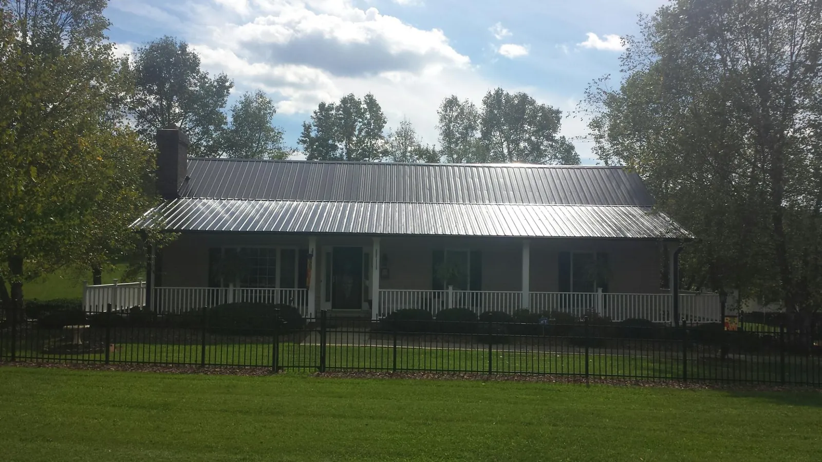 Gray metal roof on a brick ranch with a full width front porch — Gutter Guard Installation work by our crew in Great Mills