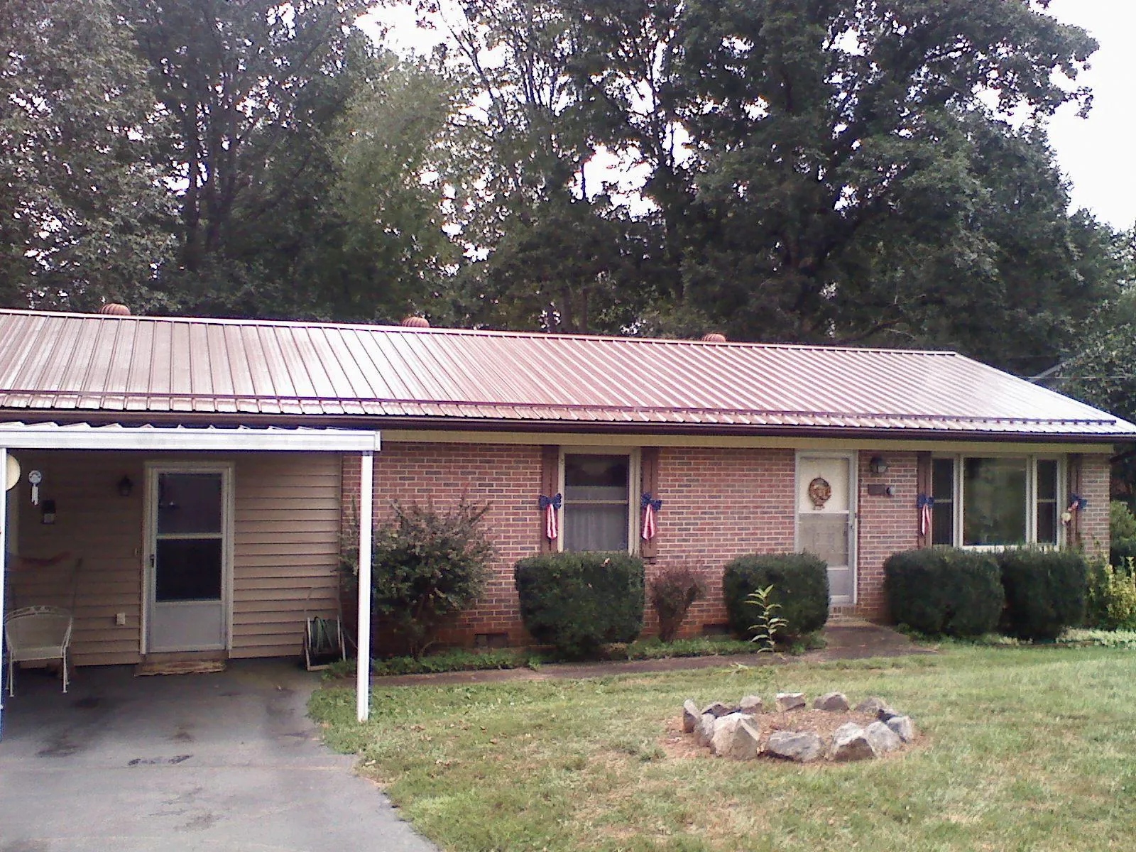 Bronze metal roof and carport on a brick ranch home — Roof Repair work by our crew in Great Mills