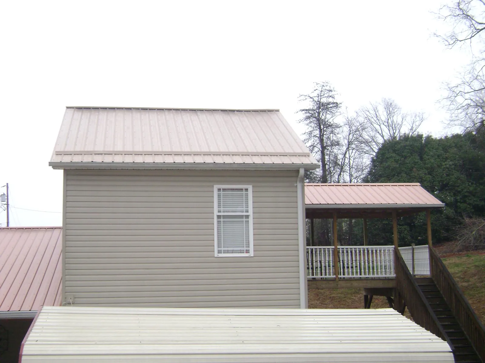 Tan metal roofs on a two story addition and attached porch, from a Roof Replacement job in Great Mills