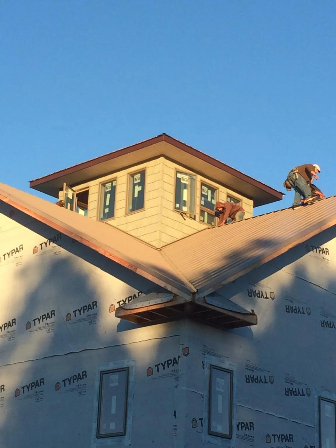 Roofers working around a rooftop cupola on a new metal roof at sunset — Roof Waterproofing in Great Mills by Roofing Brothers